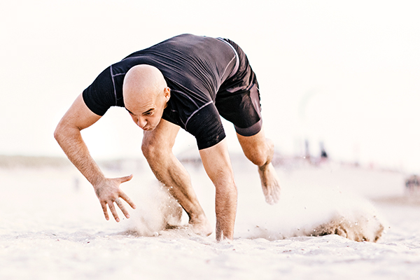 Man doing bear crawls on the beach