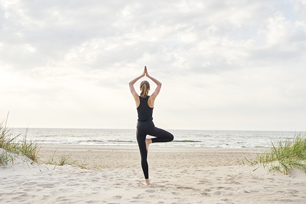 Woman in tree pose on the beach