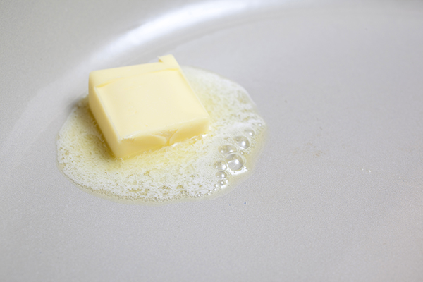 A tablespoon of butter melting in the pan.