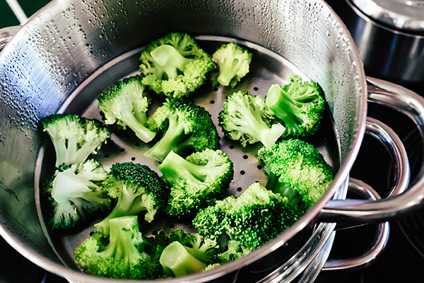 Broccoli florets being cooked in a steamer.