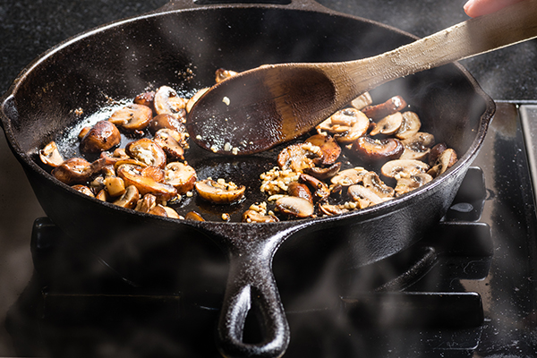 Sauteing sliced mushrooms in a cast iron skillet