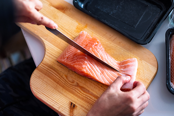 Woman slicing raw salmon on cutting board