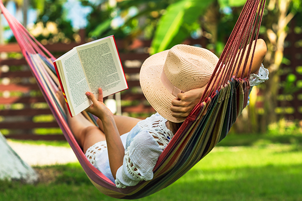 Woman reading book in hammock in tropical garden