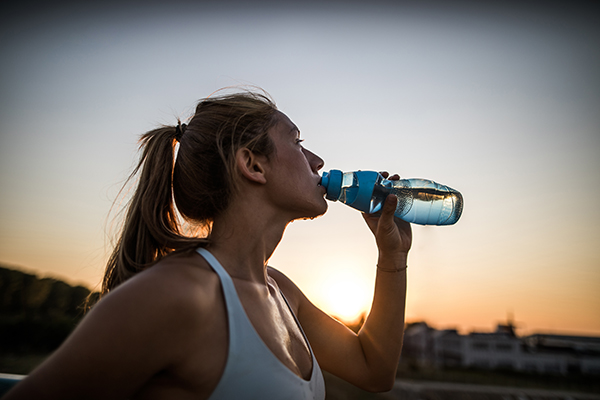 Sweaty woman outdoors drinking water
