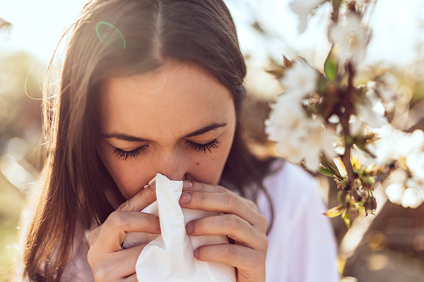 Woman coughing and sneezing outdoors.