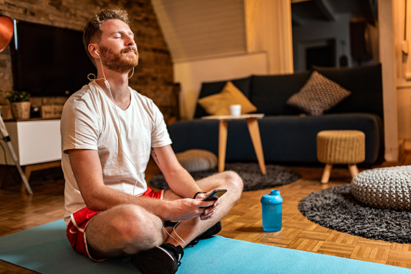 Man calming his mind with guided meditation on earphones at home.