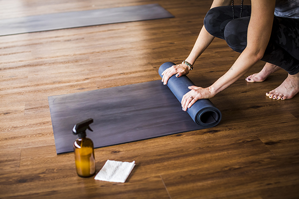 Woman cleaning, rolling up yoga mat