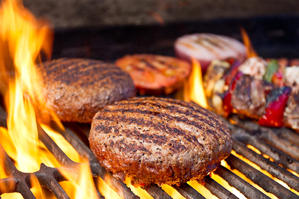 Closeup of burger, other foods on a charcoal grill