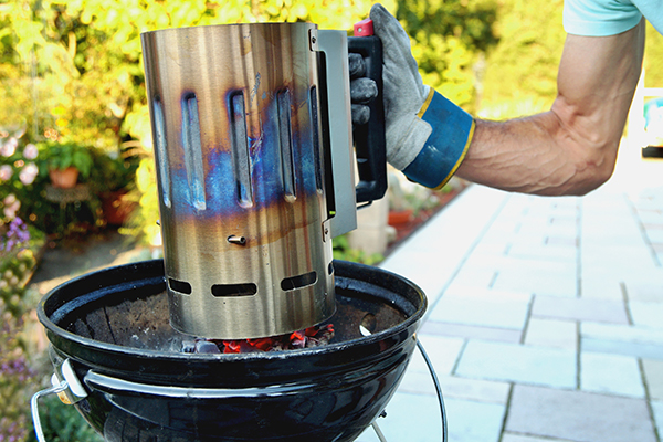 Man using chimney method to light charcoal grill