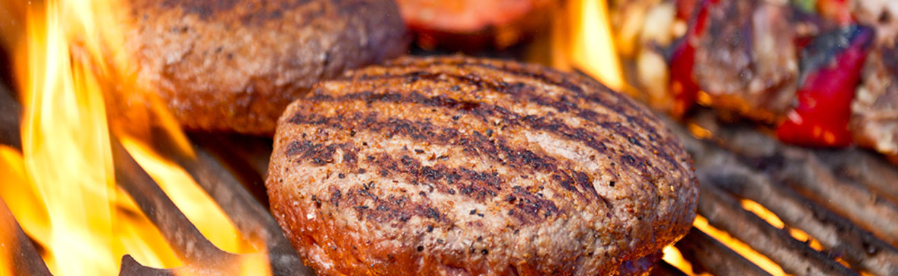 Closeup of burger, other foods on a charcoal grill