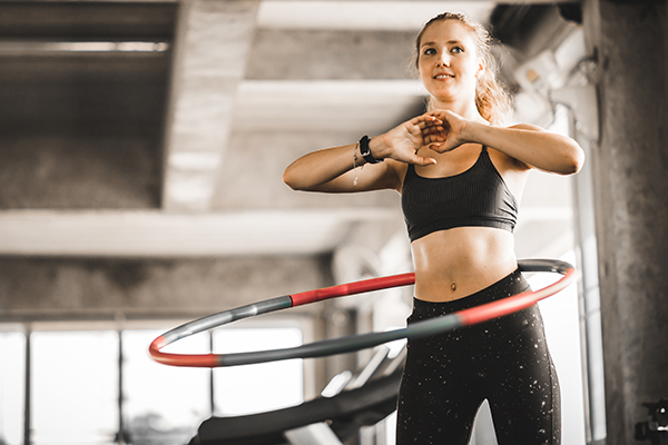 Woman using weight hula hoop in a gym