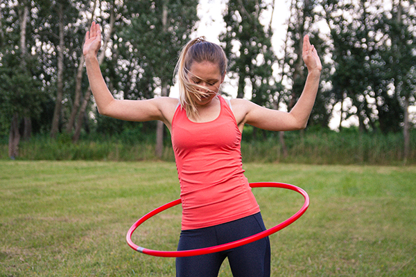 Woman using weight hula hoop outside at a park