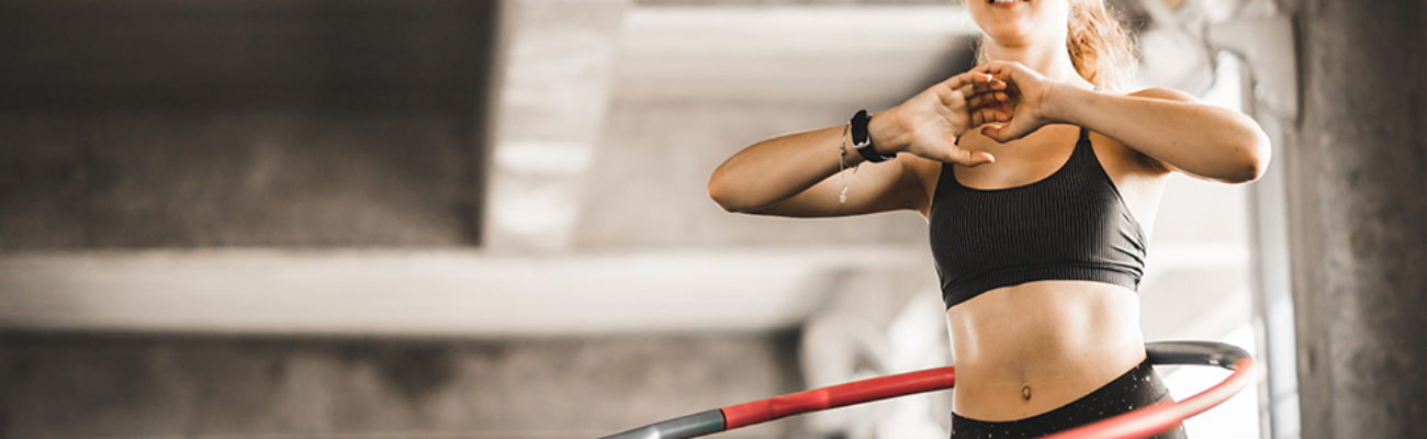 Woman using weight hula hoop in a gym