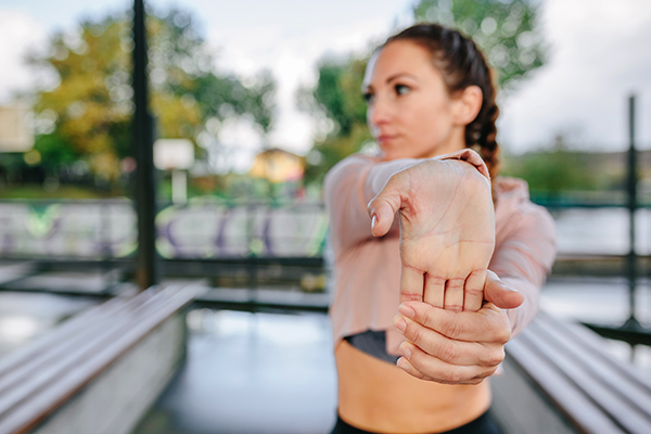 Woman stretching hands and wrist outdoors.