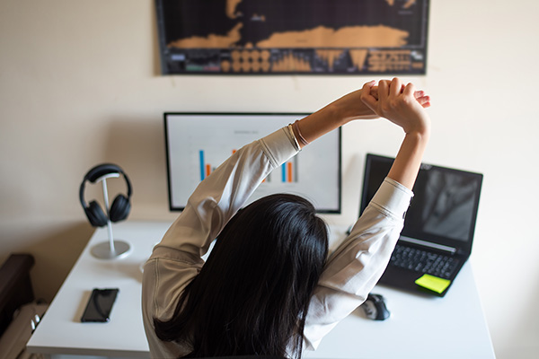 Woman stretching while working on computer from a home office