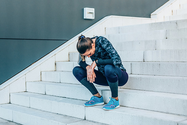 Tired female athlete sitting on stairs outside