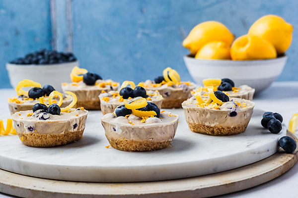 Lemon Blueberry Cheesecake Bites on marble tray, bowl of lemons, blueberries