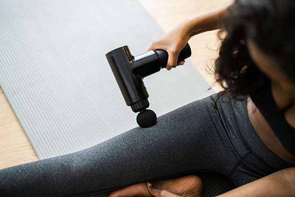 Woman using massage gun on her thigh