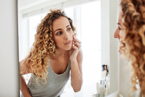 Woman checking skin in mirror
