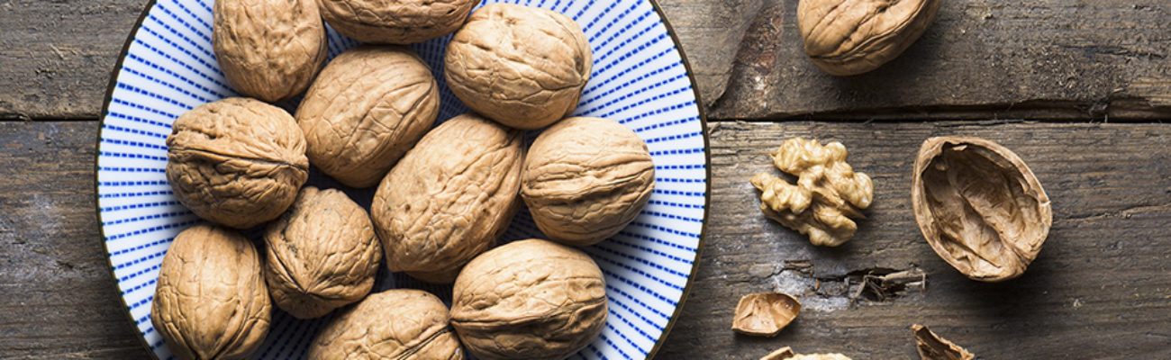A bowl of walnuts sitting on a wooden table.