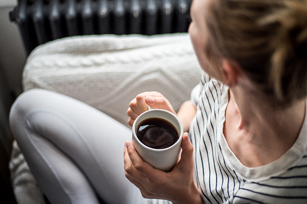 Woman holding cup of coffee on sofa