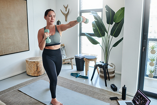 Woman exercising with dumbbells at home