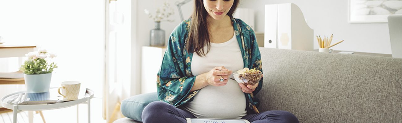 Pregnant woman sitting at home eating
