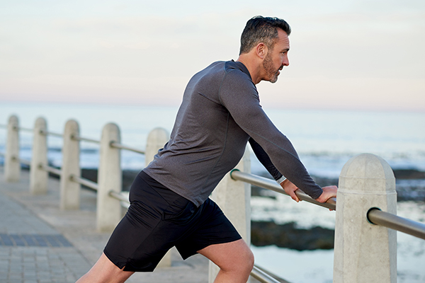 Side view of man leaning against railing stretching