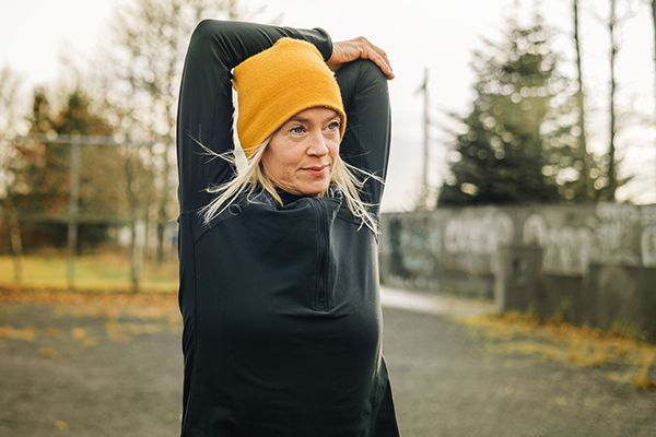 Woman jogger outside stretching her arms