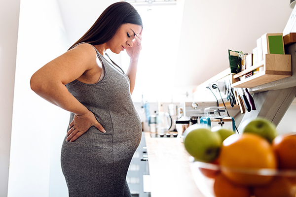 Woman standing in kitchen experiencing pregnancy brain