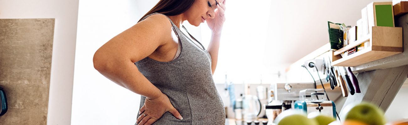 Woman standing in kitchen experiencing pregnancy brain