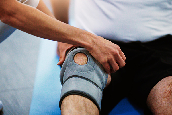 Woman putting knee brace support on patient's leg