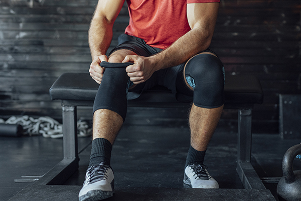 Man putting knee sleeve brace on leg