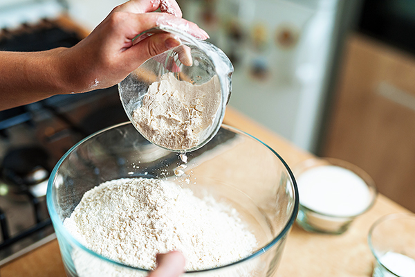 Woman pour flour into a bowl
