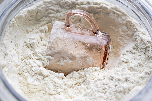 Pink glass measuring cup in a bowl of flour