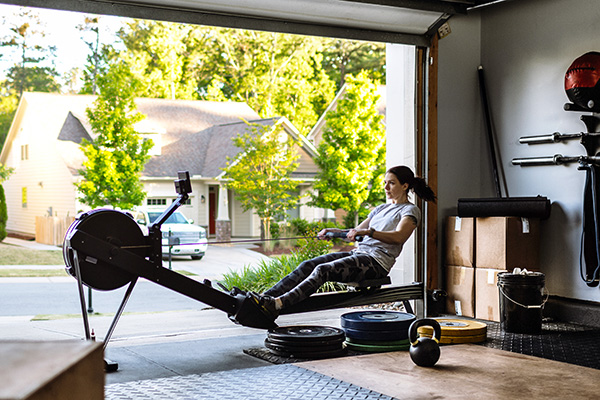 Woman using rowing machine in her home gym in garage