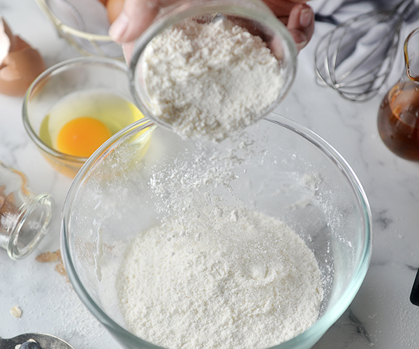 Hand pouring coconut flour into mixing bowl