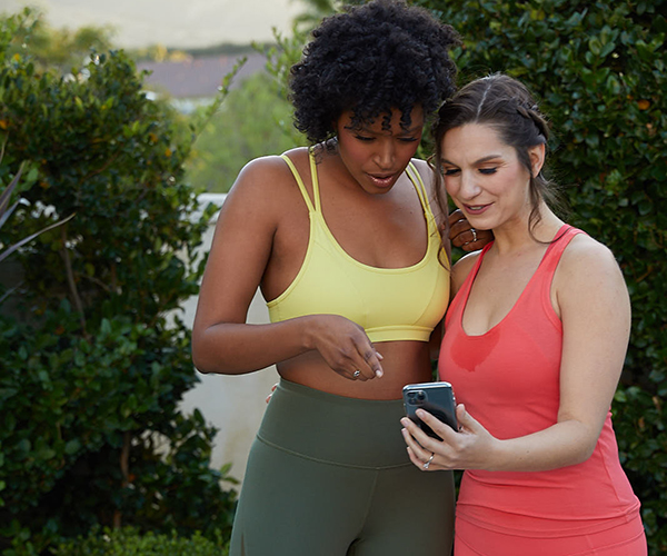 Two women checking in with their BODgroup on smartphone