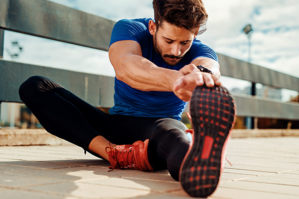 Male runner stretching leg outside