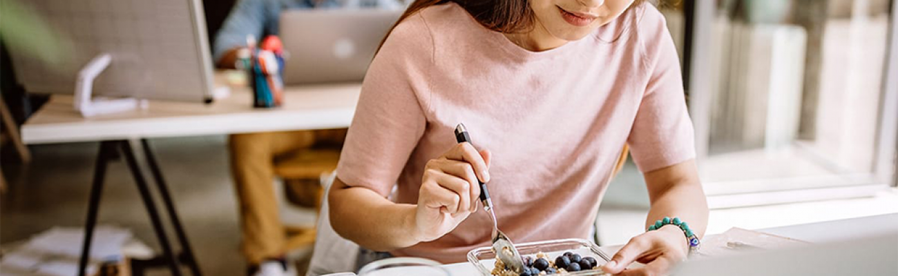 woman eating lunch at work desk | feeling sick eating healthy