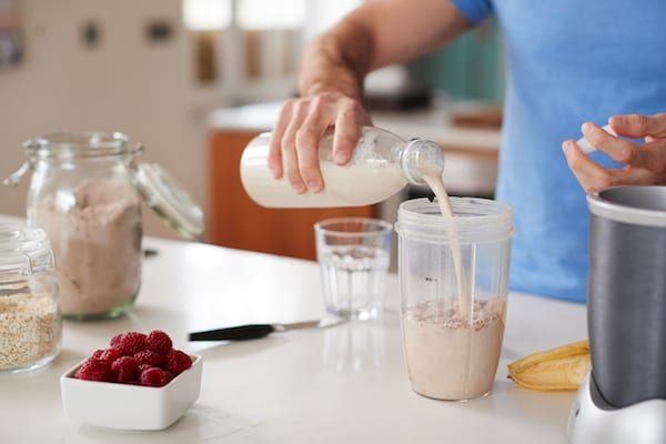 pouring milk into blender | do protein shakes make you fat