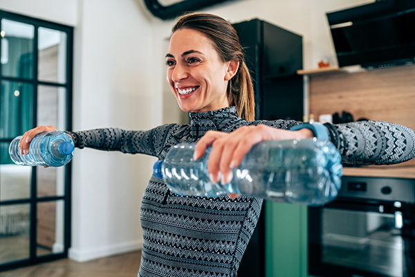 Woman exercising with water bottles for weights