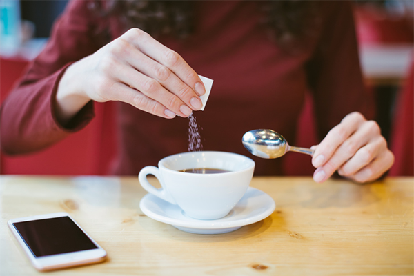 woman pouring sugar into coffee | Sugar-Free Starbucks Drinks