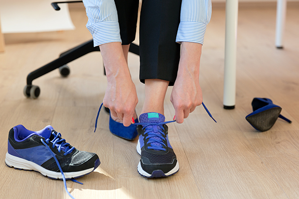 Woman changing into sneakers from high heels