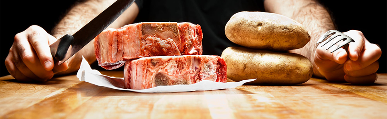 man cutting steak and potatoes | foods high in iron