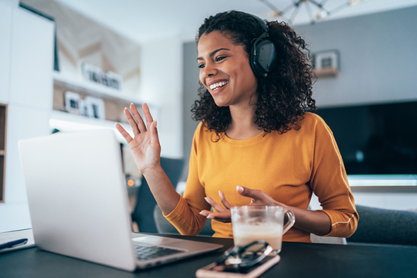 woman in headphones on computer at home | wellness routine