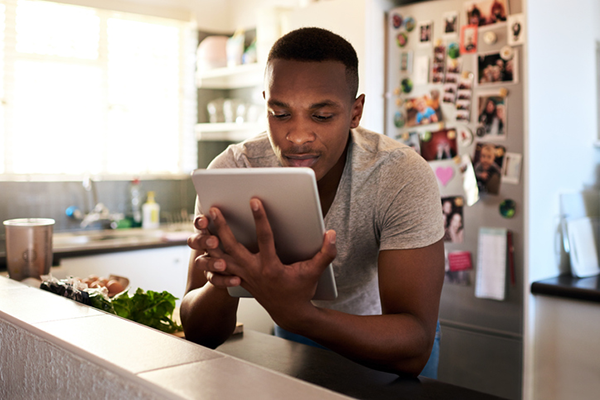 young man reading tablet ipad kitchen | calorie deficit