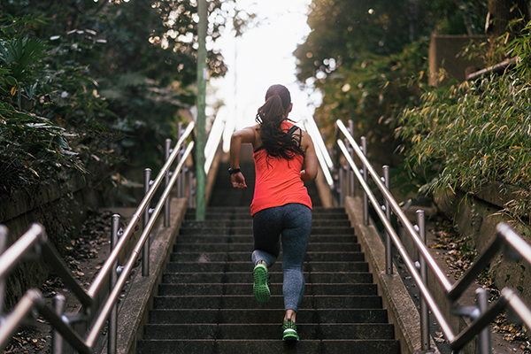 Female athlete running up stairs.