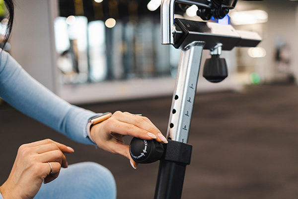 woman setting seat height stationary bike | cycling form