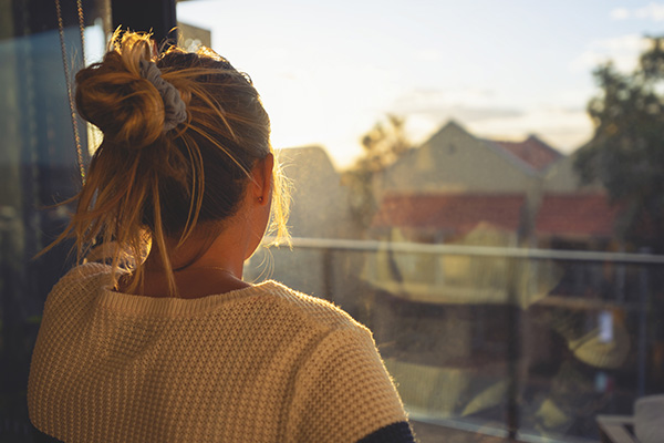 Woman looking through the window at sunset. 